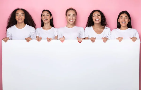 Разнообразные женщины держат пустую бумагу на розовом фоне, макет — стоковое фото
