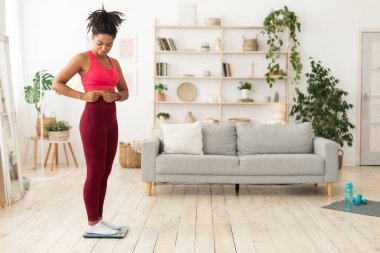 Üzgün Siyah Kız Karnına dokunuyor Evde terazide duruyor