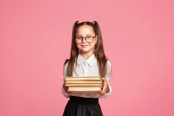 Kocka és okos kölyök. Aranyos kis iskoláslány szemüvegben és egyenruhában könyveket tart. — Stock Fotó