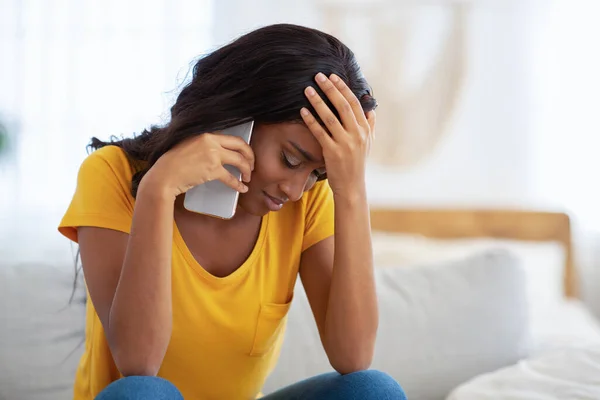 Upset African American woman talking on smartphone at home, copy space — Stock Photo, Image