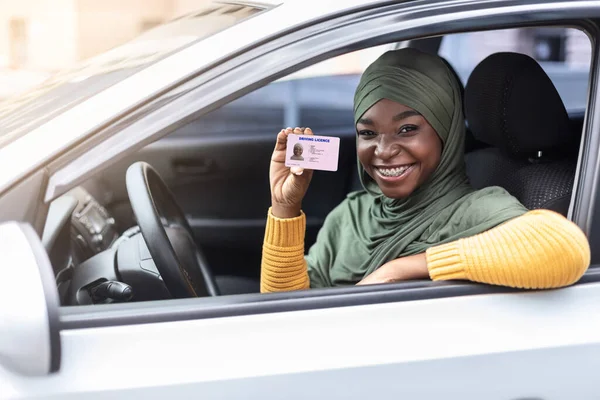 히잡을 차에 앉아 운전 면허증을 보여 주는 행복 한 흑인 여성 — 스톡 사진