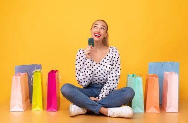 Elinde plastik kartla hayalperest bir kadın satın almayı düşünüyor.