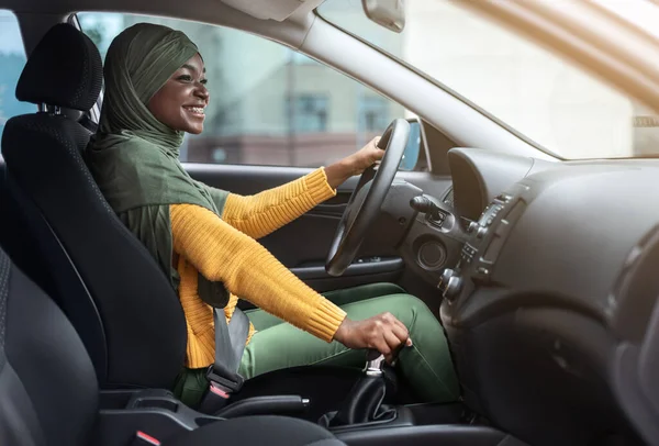 Portret van vrolijke Afrikaanse moslim vrouw in hoofddoek in nieuwe auto — Stockfoto