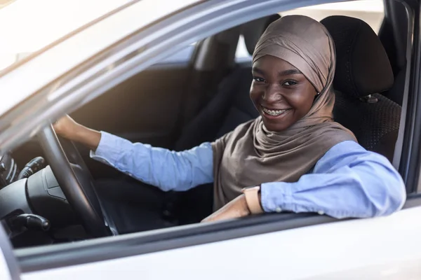 Portret van vrolijke jonge zwarte zelfverzekerde moslim vrouw poseren in haar auto — Stockfoto