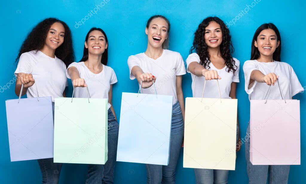 Five Women Showing Blank Shopping Bags Standing Over Blue Background