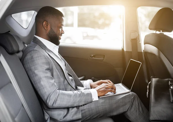 Schwarzer Geschäftsmann arbeitet an Laptop mit leerem Bildschirm — Stockfoto