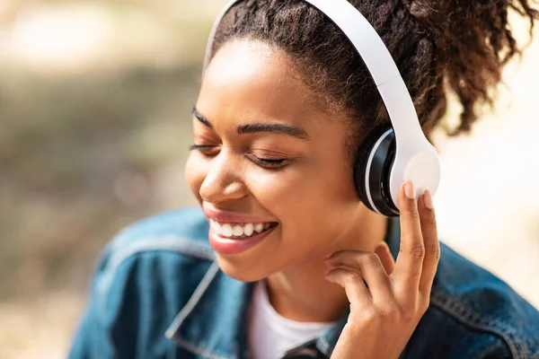 Czarny dziewczyna w słuchawki słuchanie muzyka z oczy zamknięte na zewnątrz — Zdjęcie stockowe