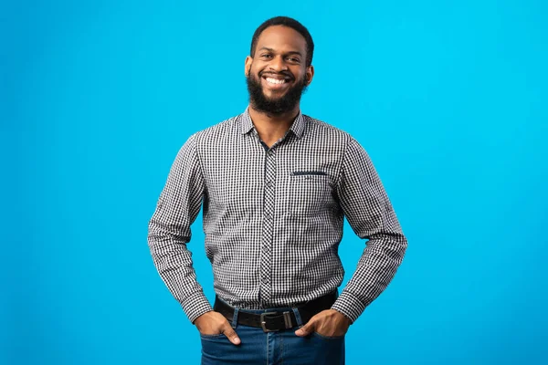 Sonriente hombre negro posando sobre fondo azul — Foto de Stock