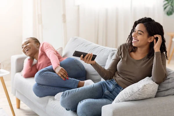 Δύο χαριτωμένα μαύρα κορίτσια βλέποντας τηλεόραση στον καναπέ — Φωτογραφία Αρχείου