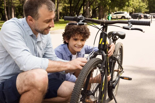 Closeup portrait of cheerful dad and son fixing bike — Stock Photo, Image