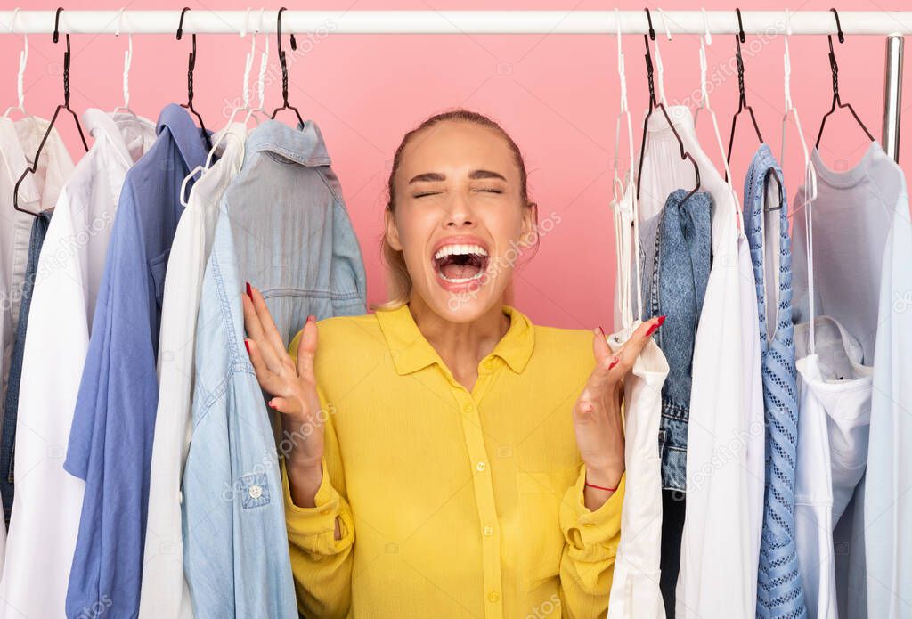 Portrait of excited woman screaming standing near rack