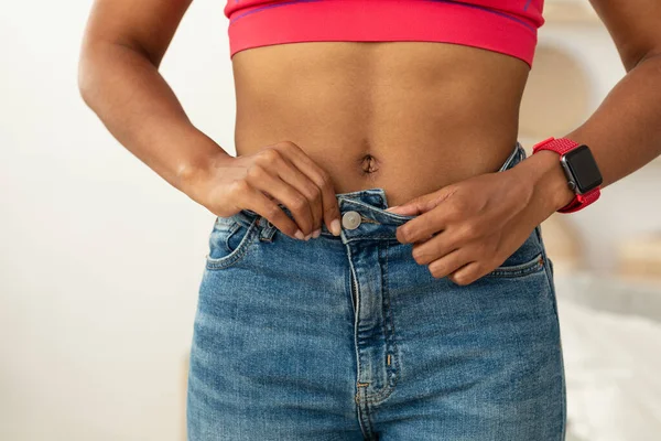 Μαύρο κορίτσι μετά την απώλεια βάρους Buttoning Skinny τζιν εσωτερικούς χώρους, περικοπεί — Φωτογραφία Αρχείου