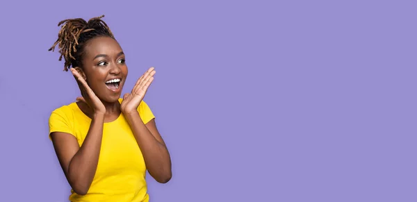 Удивлённая чёрная девушка смотрит на пространство для копирования на фиолетовом — стоковое фото
