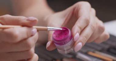Profesyonel makyöz, el derisine sıvı pembe ruj sürüyor.