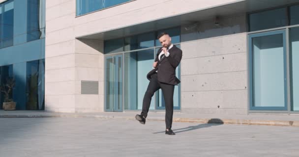 Szczęśliwy biznesmen cieszący się kontraktem, tańczący przed budynkiem biurowym — Wideo stockowe