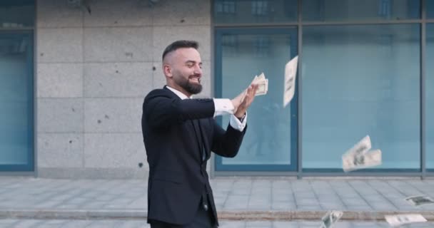 Χαρούμενος μεσήλικας επιχειρηματίας που πετάει χαρτονομίσματα δολαρίων, περπατώντας κοντά σε κτίριο γραφείων σε εξωτερικούς χώρους — Αρχείο Βίντεο
