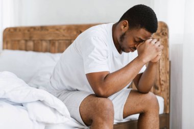Evde yatağında uykusuzluk çeken depresif Afrikalı adam.