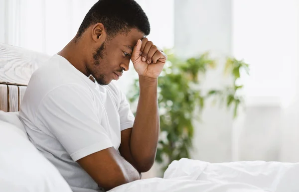 Deprimido Africano Guy sentado na cama pensando em problemas internos — Fotografia de Stock