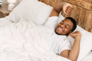 Dinlenmis siyah adam uyaniyor ve yatakta yatiyor.