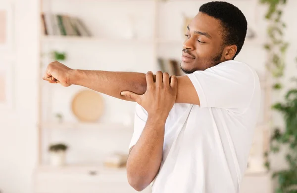自宅で腕のストレッチトレーニングを行使黒人男性 — ストック写真