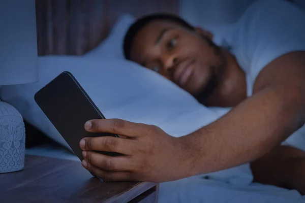 Ο τύπος διαβάζει το μήνυμα στο τηλέφωνο ξαπλωμένος στο κρεβάτι τη νύχτα — Φωτογραφία Αρχείου