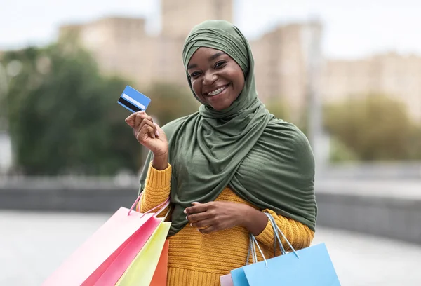 Siyah Musim Kadın Renkli alışveriş çantaları ve kredi kartı ile dışarıda poz veriyor — Stok fotoğraf