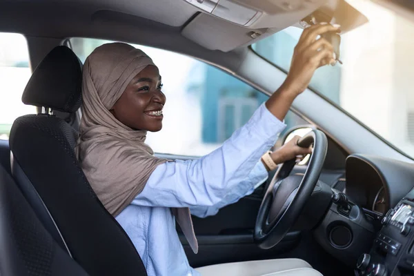 Nieuwe auto kopen. Moslim Afrikaanse dame in hidjab aanpassen achteruitkijkspiegel — Stockfoto