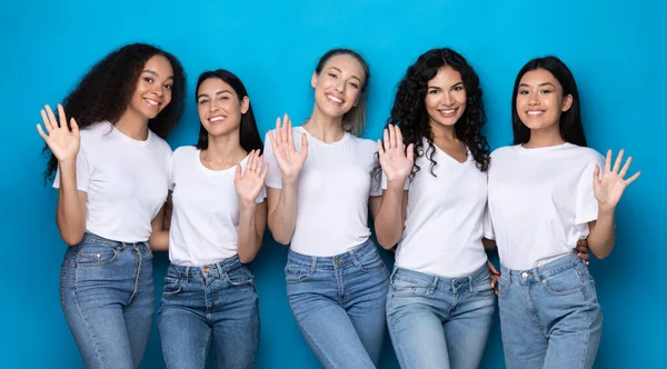 Cinco mulheres multiétnicas acenando mão sorrindo posando em fundo azul — Fotografia de Stock
