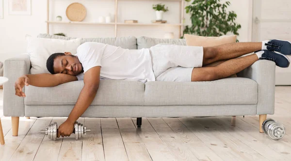 Afro-Amerikaanse man slapen houden dumbbell liggend op bank Indoor — Stockfoto