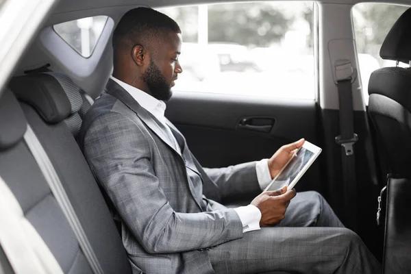 Konzentrierter Schwarzer mit digitalem Tablet im Auto — Stockfoto