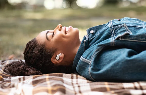 Relaxed African American Girl Słuchanie muzyki leżącej na kratę na zewnątrz — Zdjęcie stockowe