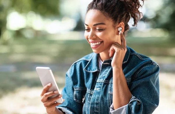 Noir Millennial fille à l'aide de téléphone faisant appel vidéo Siitting extérieur — Photo