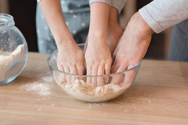 Zbliżenie męskich i dziecięcych rąk ugniatających ciasto w misce — Zdjęcie stockowe