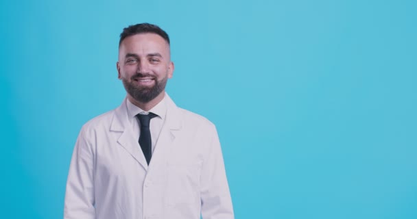 Retrato de estudio de médico amigable, fondo azul, espacio libre — Vídeo de stock