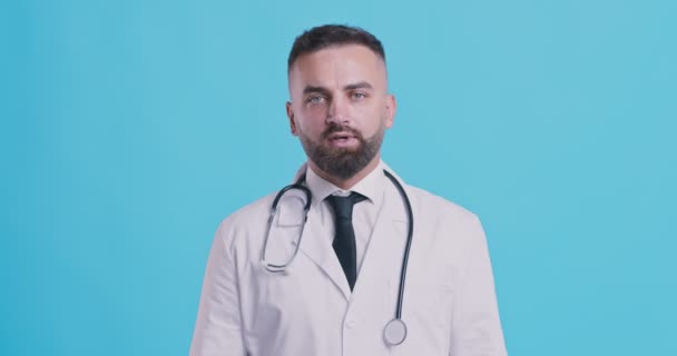Portrét seriózního lékaře ukazující ne, zkřížené ruce jako stopka, negační gesto, modré pozadí studia. — Stock video