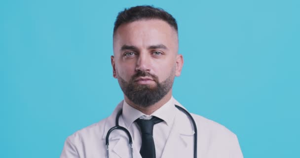 입술에 손가락을 쥐고 있는 심각 한 의사의 모습, 푸른 스튜디오 배경 — 비디오