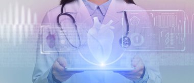 Cerrah teknolojik dijital hologramı inceliyor. Tablet hastanın parlayan kalbini temsil ediyor.