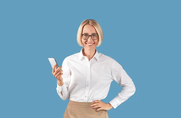 Retrato de empresária com telefone celular trabalhando on-line ou conversando com o cliente em fundo estúdio azul — Fotografia de Stock