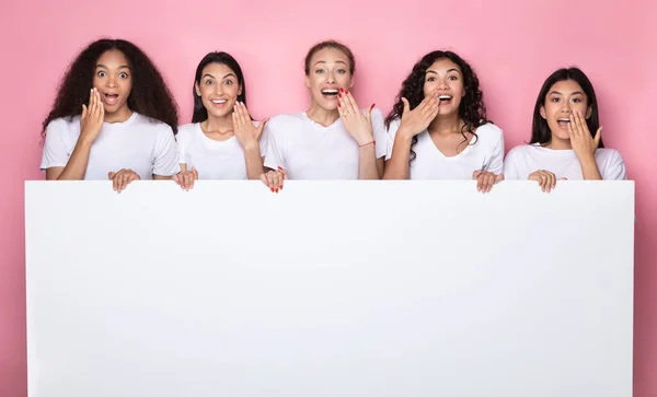 Señoras multiétnicas emocionadas sosteniendo cartel con espacio de copia, fondo rosa — Foto de Stock