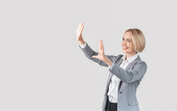 Bella donna d'affari caucasica in abito da ufficio in piedi su sfondo chiaro e fare gesto cornice, spazio copia — Foto Stock