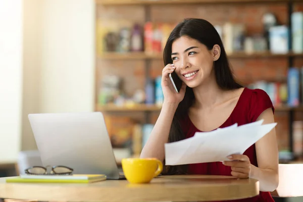 Remote Office. Junge asiatische Geschäftsfrau arbeitet mit Papieren und Telefon im Café — Stockfoto