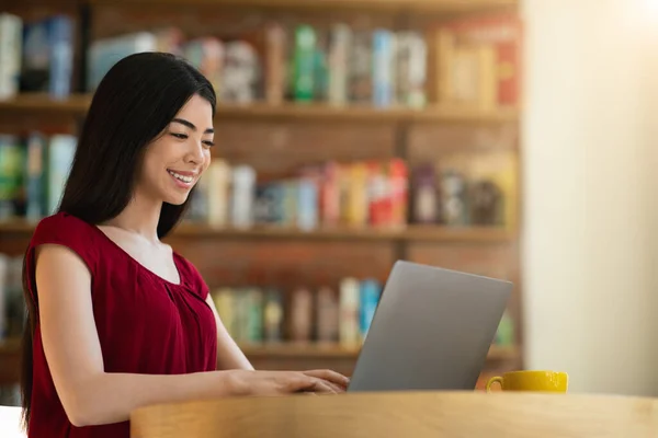 Smilende asiatisk kvinnelig student som forbereder seg til undervisning med Laptop i kafe – stockfoto