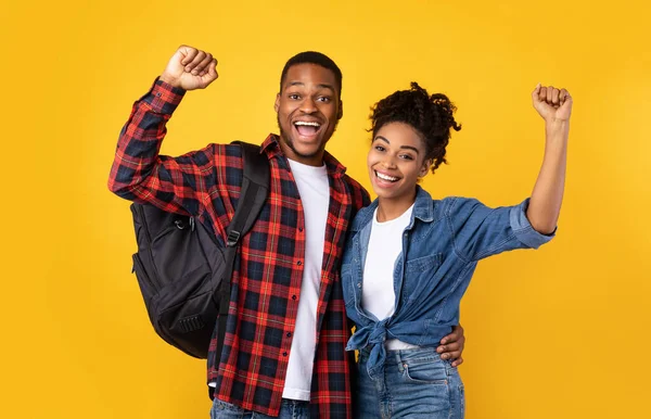 Heureux couple de touristes noirs avec sacs à dos Gesturing Oui, fond jaune — Photo