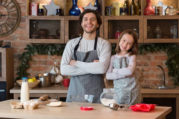 Ev Fırıncıları. Mutlu baba ve küçük kız mutfakta önlüklü poz veriyorlar.