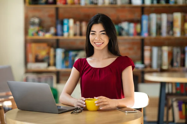 Negocio remoto. Joven mujer empresaria asiática trabajando en portátil y disfrutando del café — Foto de Stock