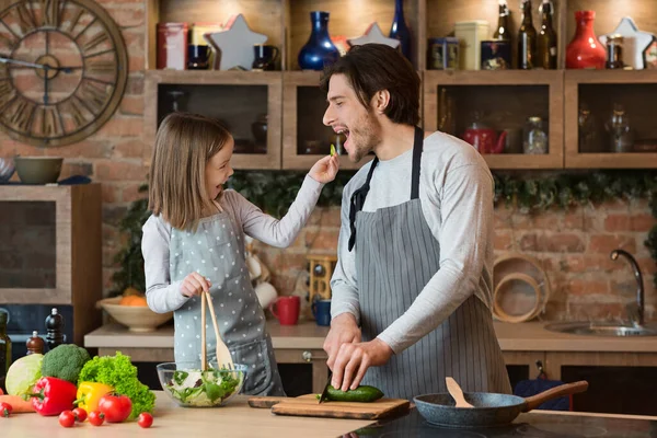 Mutlu genç aile babası ve kızı mutfakta yemek pişirirken eğleniyor.