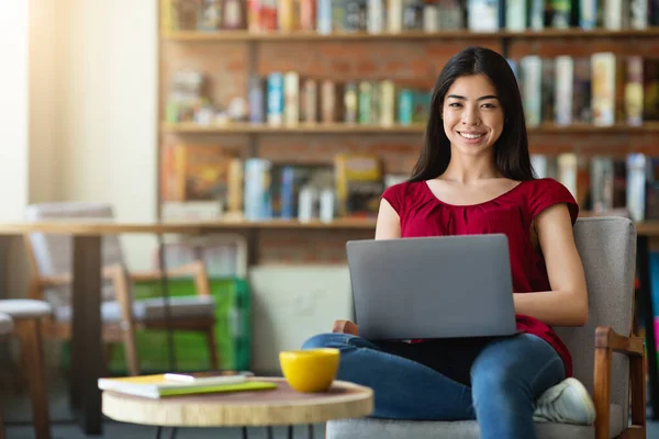 移动办公室。快乐的亚洲女自由撰稿人与笔记本电脑坐在咖啡店里 — 图库照片