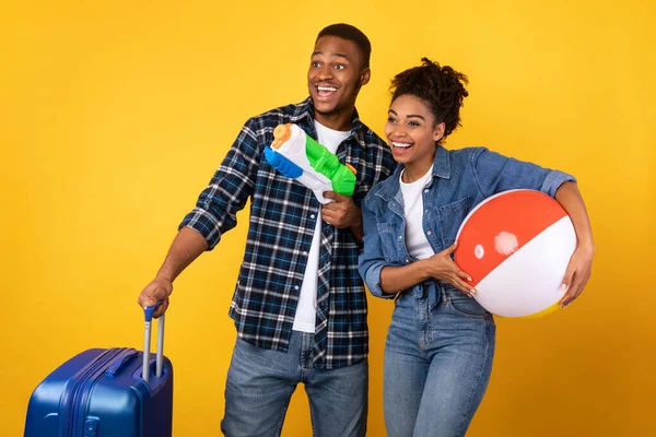 Bavul ve oyuncaklarla eğlenen çift, sarı arka plan