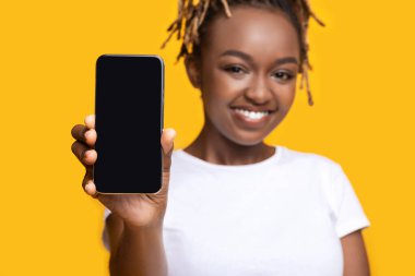 Neşeli siyah kadın boş ekranlı akıllı telefon gösteriyor.