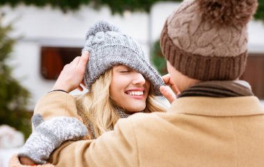 Adam kış buluşmasında kız arkadaşının örgü şapkasıyla oynuyor.